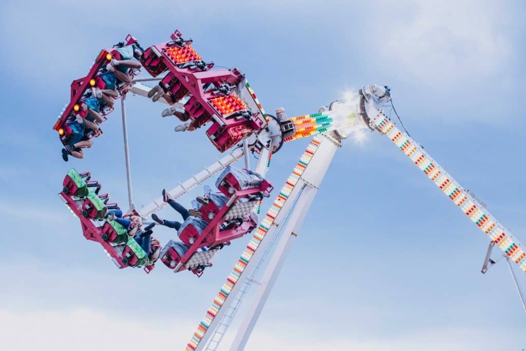 People ride an upside-down amusement park ride against a cloudy sky backdrop.